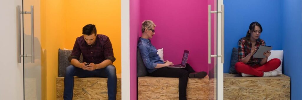 three people in colourful cubicles that are side-by-side.