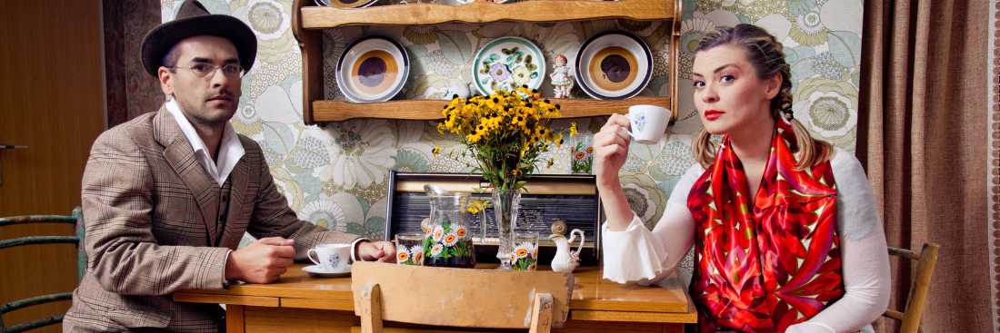 Retro couple drinking tea or coffee at table.