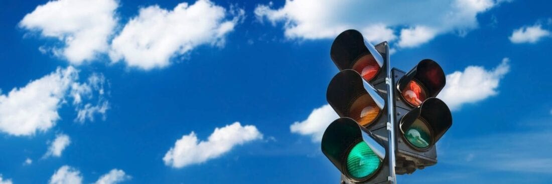 A traffic light with a blue sky & cloud background.