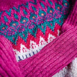 A closeup of a pink knitted jumper with retro vibes.