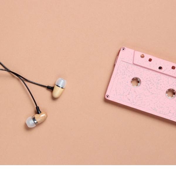 Audio cassette and headphones on pink-brown background.